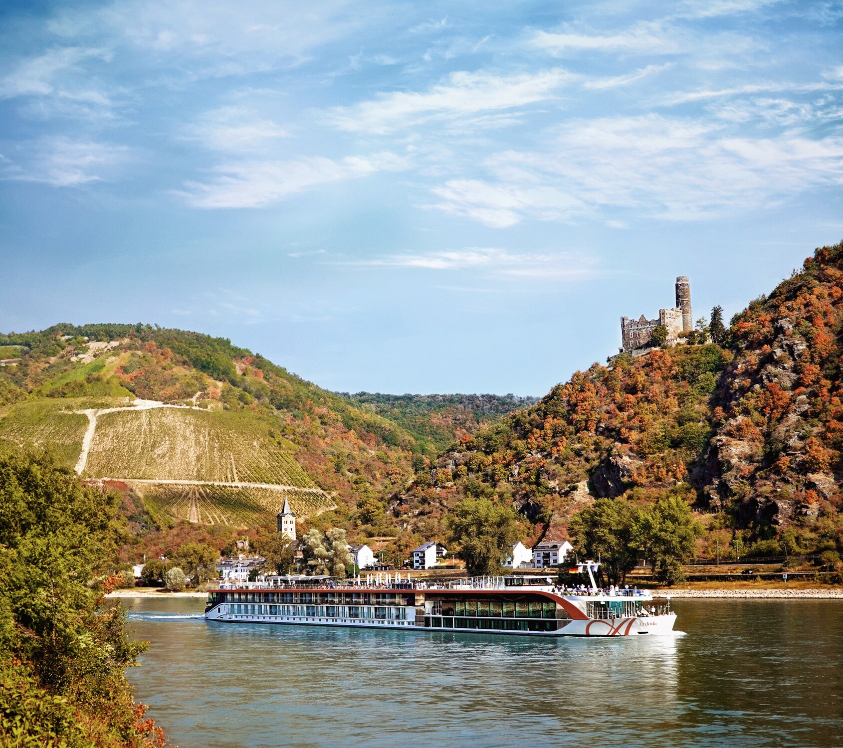 AmaWaterways river ship sailing past European vineyards and a hilltop castle