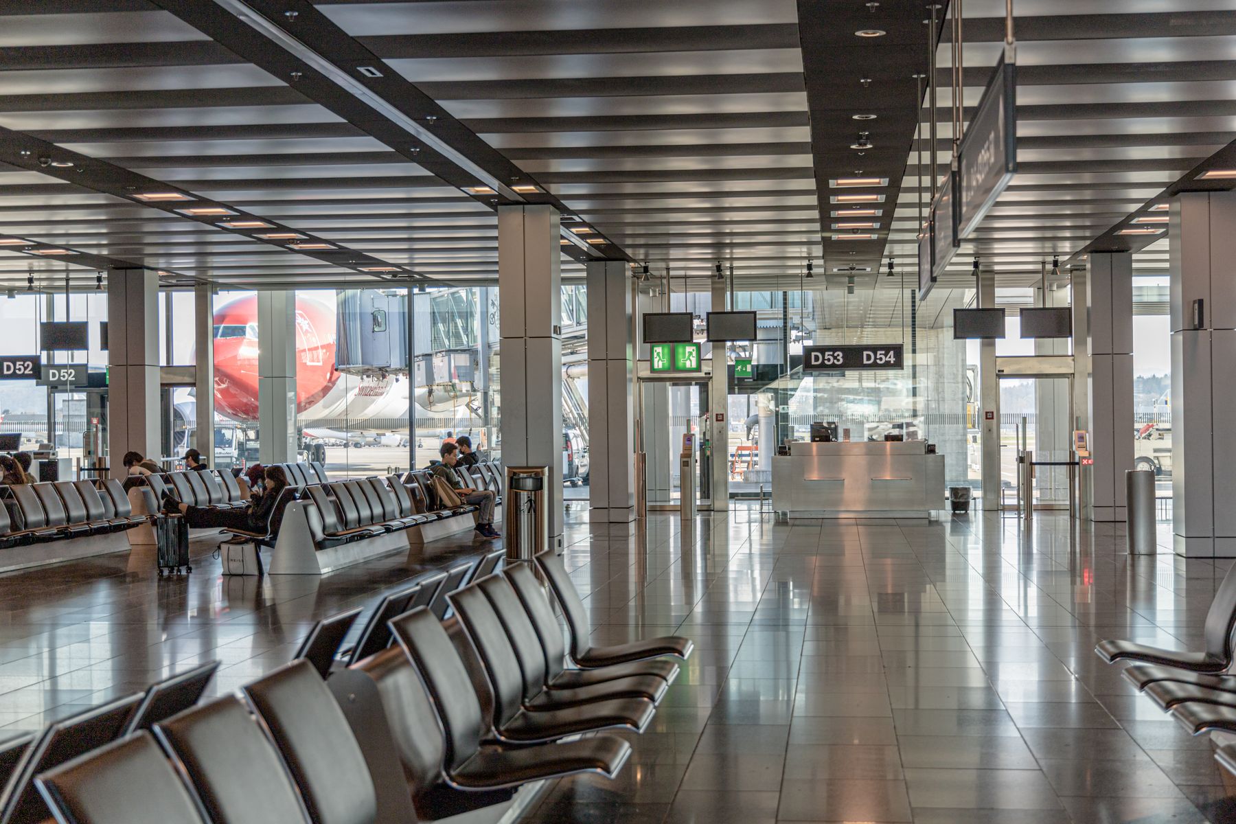 Airport departure lounge with an airplane visible through the terminal windows